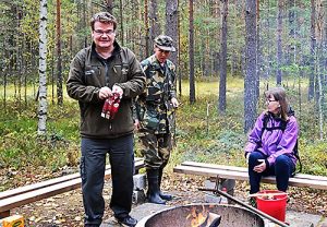 Mies seisoo kahvipussi kädessä nuotion vieressä